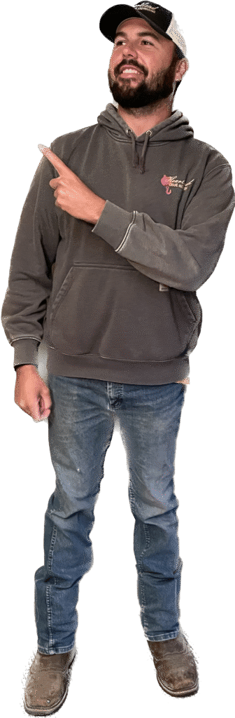 a man wearing a gray hoodie and a black hat pointing upwards