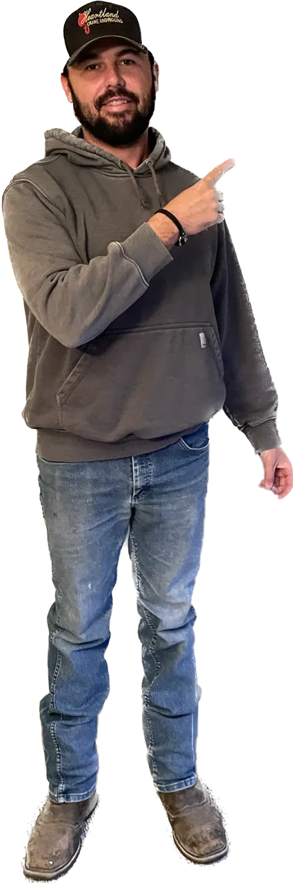 a man wearing a gray hoodie and a black hat pointing upwards